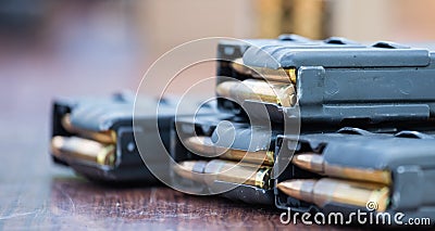 Magazines with bullets of firearm putted on wooden table. Close up view, blurred background. Stock Photo