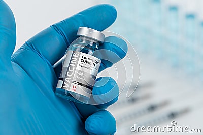 Blue Medical Glove Holding Coronavirus COVID-19 Vaccine Vial Stock Photo