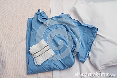 Blue medical operation shirt and white operation underware lying on a hospital bed Stock Photo