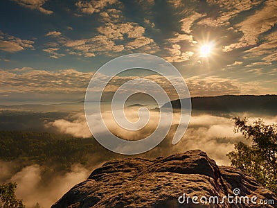 Blue misty daybreak. Sandstone cliff above deep foggy valley in mountains. Stock Photo