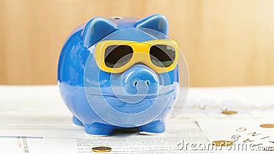 Blue money box of pig form with sunglasses stands on table Stock Photo