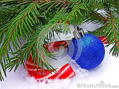 Blue New Year ball and Christmas caramel candy with green fir tree on snowy background Stock Photo