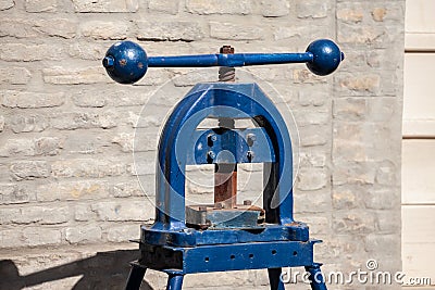 Blue old printing press, manual, on display on a brick wall. Such printing presses were used to manually print books and other Stock Photo