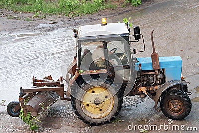 Blue old and rusty tractor running after rain storms Stock Photo