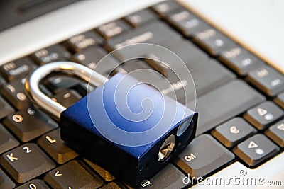 Internet and computer systems security concept: blue padlock closed on top of laptop computer keyboard Stock Photo