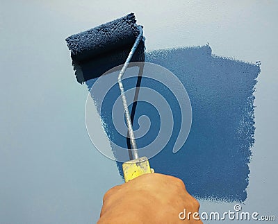 Blue paint roller on the wall Stock Photo