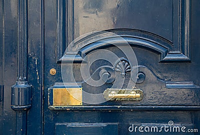 Blue painted antique door closeup with curved frame and elegant volute carving wooden panel with shiny brass plate and door handle Stock Photo