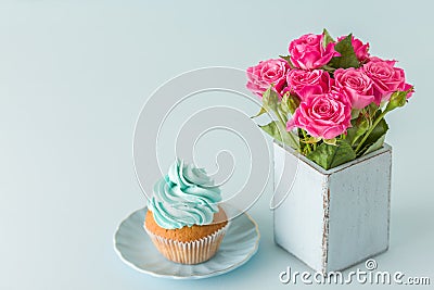 Blue pastel horizontal banner with top view of decorated with blue cream cupcake and pink roses in retro shabby chic vase. Stock Photo