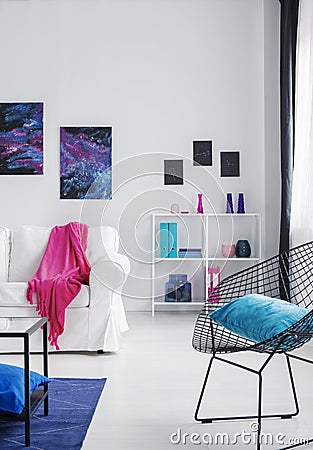 Blue pillow on black stylish metal armchair in bright cosmos inspired interior with white furniture, real photo with copy space on Stock Photo