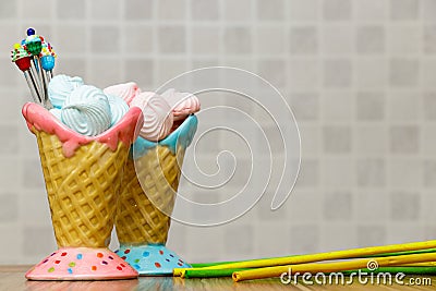 Blue and pink meringue in the pink and blue cones with cupcakes, green and yellow sticks on wood table white background Stock Photo