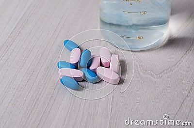 Blue and pink probiotic pills or vitamins on a wooden background. Pharmacology theme Stock Photo