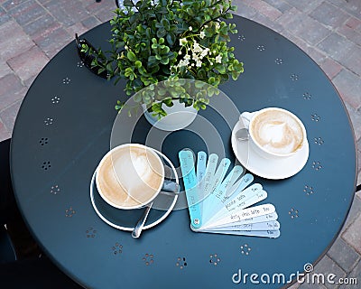 Blue planks menu with various drinks names and cups of coffee on blue table Stock Photo