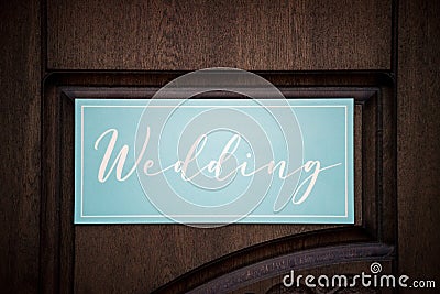 A blue plate in the form of an arrow and a pointer with the inscription and letters wedding in English stands in nature at the Stock Photo