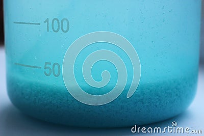 Blue precipitate of copper carbonate precipitated at the bottom of a beaker. Stock Photo