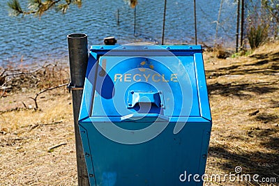 Blue recycle bin along lakeside hiking trail Stock Photo