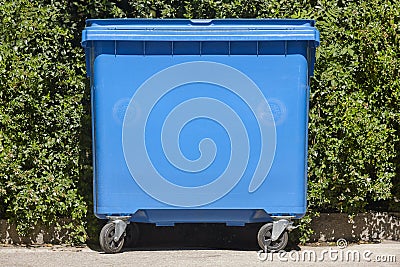 Blue recycling container for paper with green bush background Stock Photo