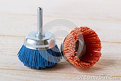 Blue and red nylon abrasive brushes for drill on a white wooden surface. Tools for cleaning, polishing and grinding of wood and Stock Photo