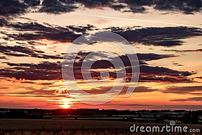 Blue red sky background with evening fluffy curly rolling clouds with setting sun. Good windy weather Stock Photo