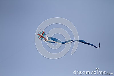 A blue red white kite flying against a blue sky. Klite flying in the blue sky Stock Photo