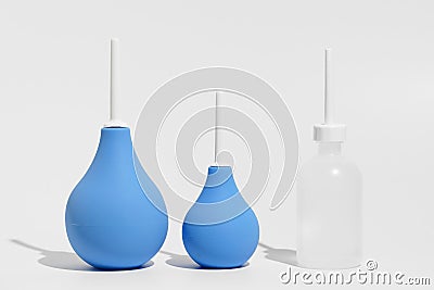 Blue rubber enemas and transparent enema filled with water on gray isolated background. The concept of medical and pharmaceutical Stock Photo