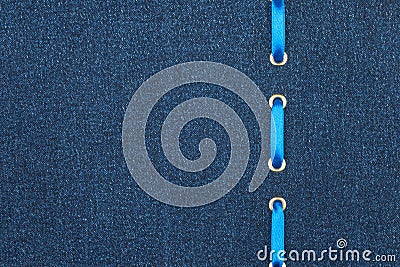 Blue satin ribbon is inserted in a dark denim fabric. View from above. Stock Photo