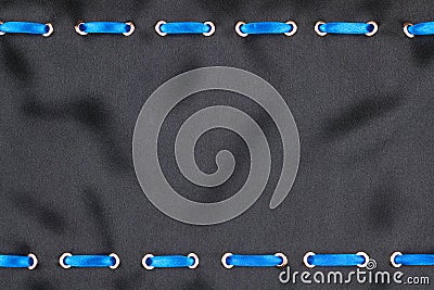 Blue satin ribbon inserted in the gold rings on black silk Stock Photo