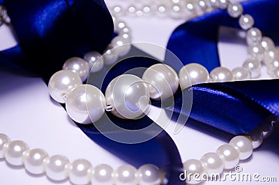 Blue satin ribbon with pearl jewelry. Luxurious decoration. For jewelry sites, blogs about fashion, style, jewelry. Snow-white Stock Photo