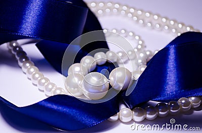 Blue satin ribbon with pearl jewelry. Luxurious decoration. For jewelry sites, blogs about fashion, style, jewelry. Snow-white Stock Photo