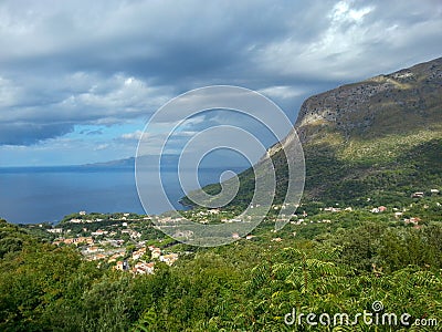 Blue and blue sea, city, rocks under the sky with clouds and fancy shadows on the mountain, Maratea, Basilicata, Italy Stock Photo