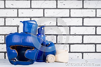 Blue set of helmet and boxing gloves for sports on the background of a brick wall, on the right there is a place for inscription Stock Photo