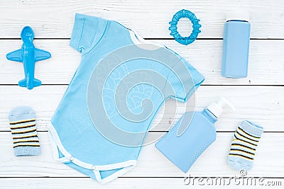 Blue set for newborn boy. Baby bodysuit, socks, airplan toy, oap and powder on white wooden background top view Stock Photo