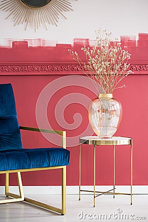 Blue settee next to small elegant table with glass vase with dry flowers Stock Photo