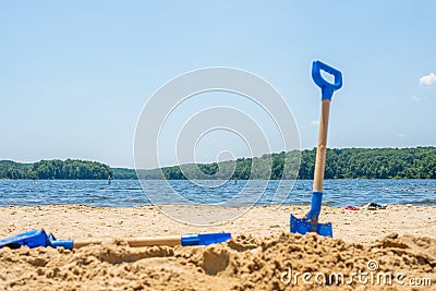 Kids beach tools blue shovel on blue water lake. Stock Photo