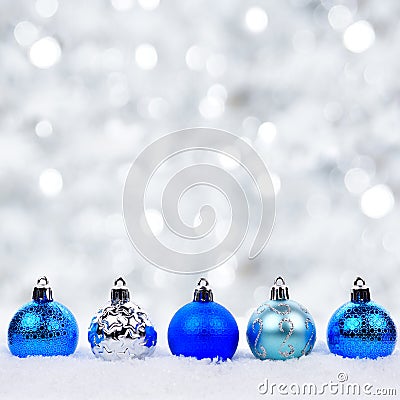 Blue and silver Christmas ornaments in snow with twinkling background Stock Photo