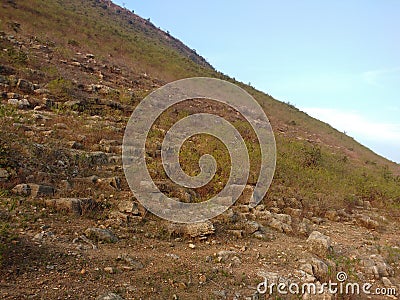 The blue sky covered the steeply hill with greenery and rocks Stock Photo