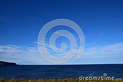 Blue sky with feathery clouds over the horizon of the ocean Stock Photo