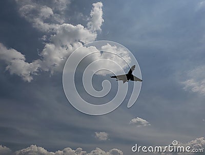blue sky with white clouds and the silhouette of a plane Stock Photo