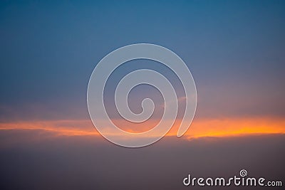 Blue sky with white fluffy clouds, orange rays of light horizontally during sunset. Stock Photo