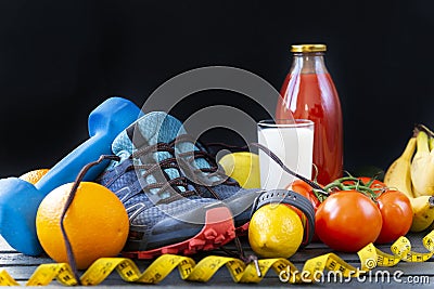 Blue sneakers, dumbbells, fruits, vegetables, measuring tape, food, lemon, orange, tomato, bananas, bottle of tomato juice, glass Stock Photo