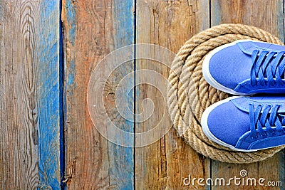 Blue sneakers shoes on a rope spiral, on a wooden weathered terrace. Yacht style concept. Stock Photo