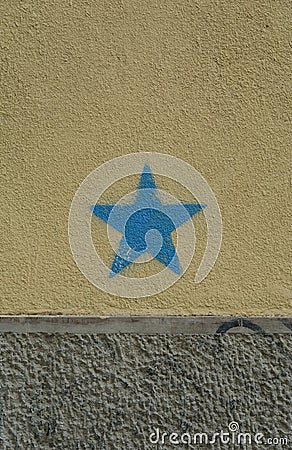 Blue star on the dirty ochre and gray wall. A concept photograph. Stock Photo