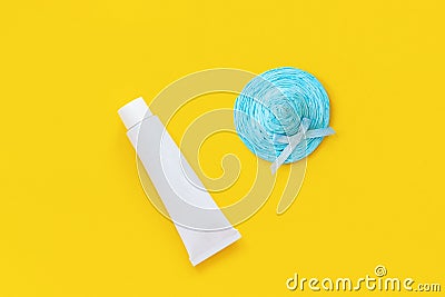 Blue straw hat and white tube of sunscreen on yellow paper background. Mock up Template for lettering, text or your design Stock Photo