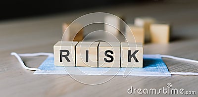 Blue surgical face mask with wood block word RISK. Coronavirus. Healthcare, Medical concept Stock Photo