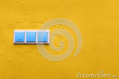 Blue switches on a yellow concrete wall. Colorful electrical switch. Creative style. Copy space Stock Photo