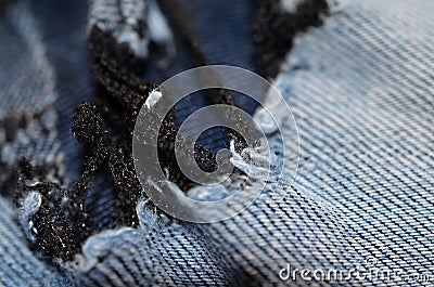 Blue texture maden from a piece of jeans with torned hole with threads blurred toned. Stock Photo