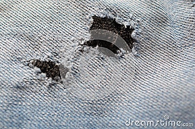 Blue texture maden from a piece of jeans with torned hole with threads blurred toned. Stock Photo