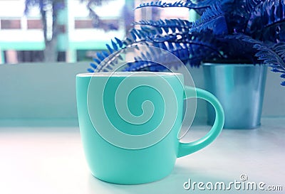 Blue tone colored pop art style coffee cup with the potted fern in the backdrop Stock Photo