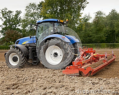 Blue Tractor Pulling Power Harrow Stock Photo