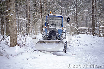 blue tractor skidded by snow, it stands in a forest strip Stock Photo