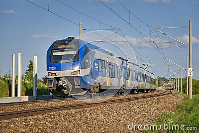 blue train on tracks under overhead power lines at a station Editorial Stock Photo
